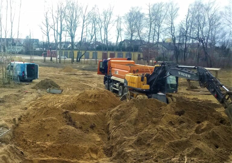 Na zdjęciu rozkopana ul. Brzechwy, na środku górki piachu obok koparka któa rozgarnia piach, za koparką stoi samochód wywrotka a w tle samochód specjalistyczny WOD-KAN